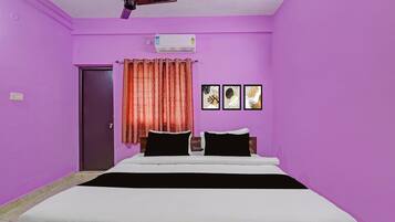 Una habitación con paredes moradas, una cama con ropa de cama blanco y negro, un ventilador de techo y un equipo de aire acondicionado.