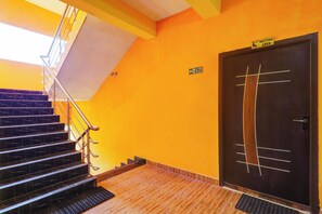 A staircase leading to a door with a fire exit sign, a wheelchair-accessible waiting area sign, and a fire exit sign on the wall.