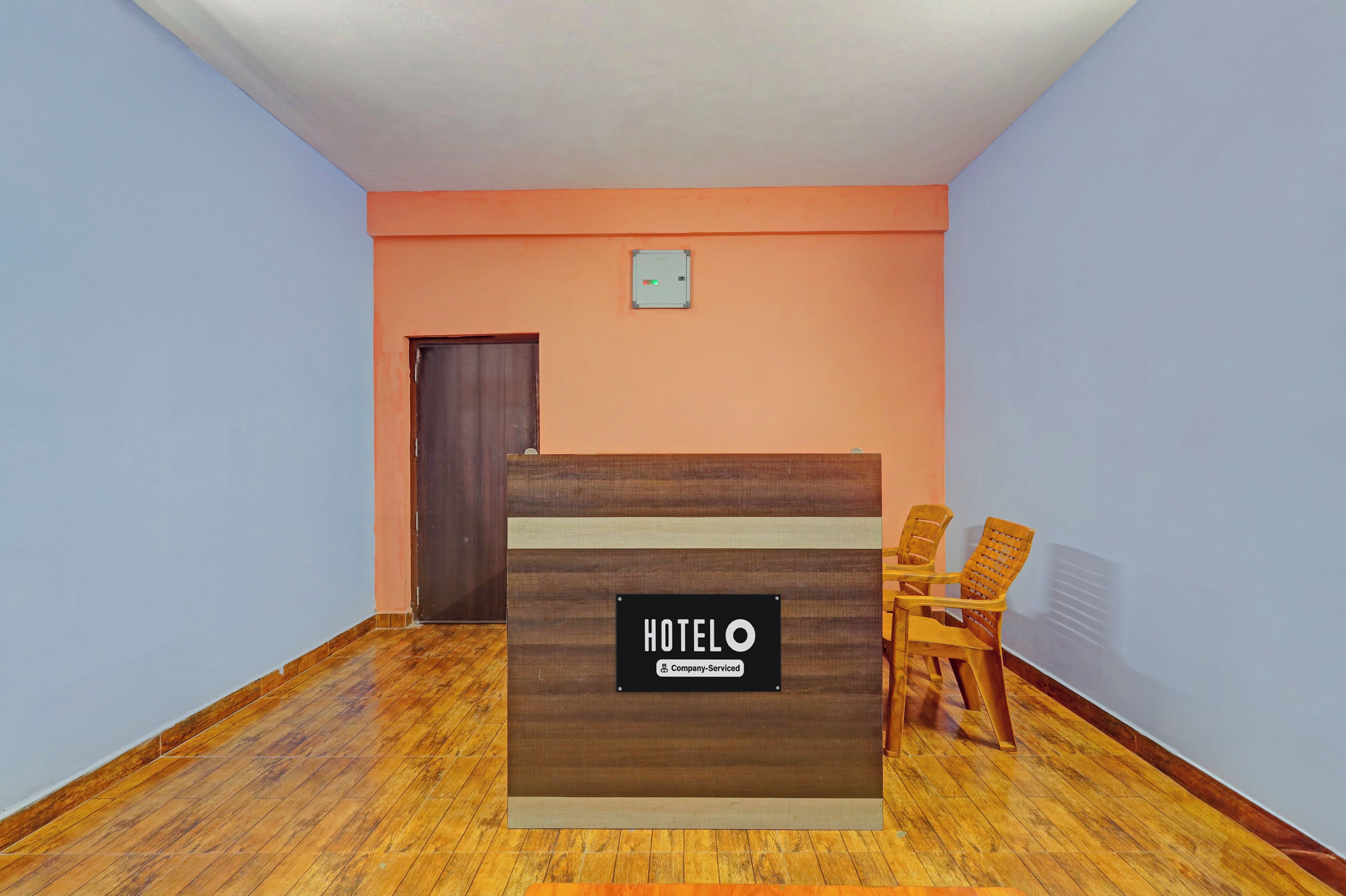Ein Hotelrezeptionstisch mit einem Schild, das angibt, dass er betrieblich genutzt wird. Zwei Holzsessel befinden sich rechts neben dem Tisch.