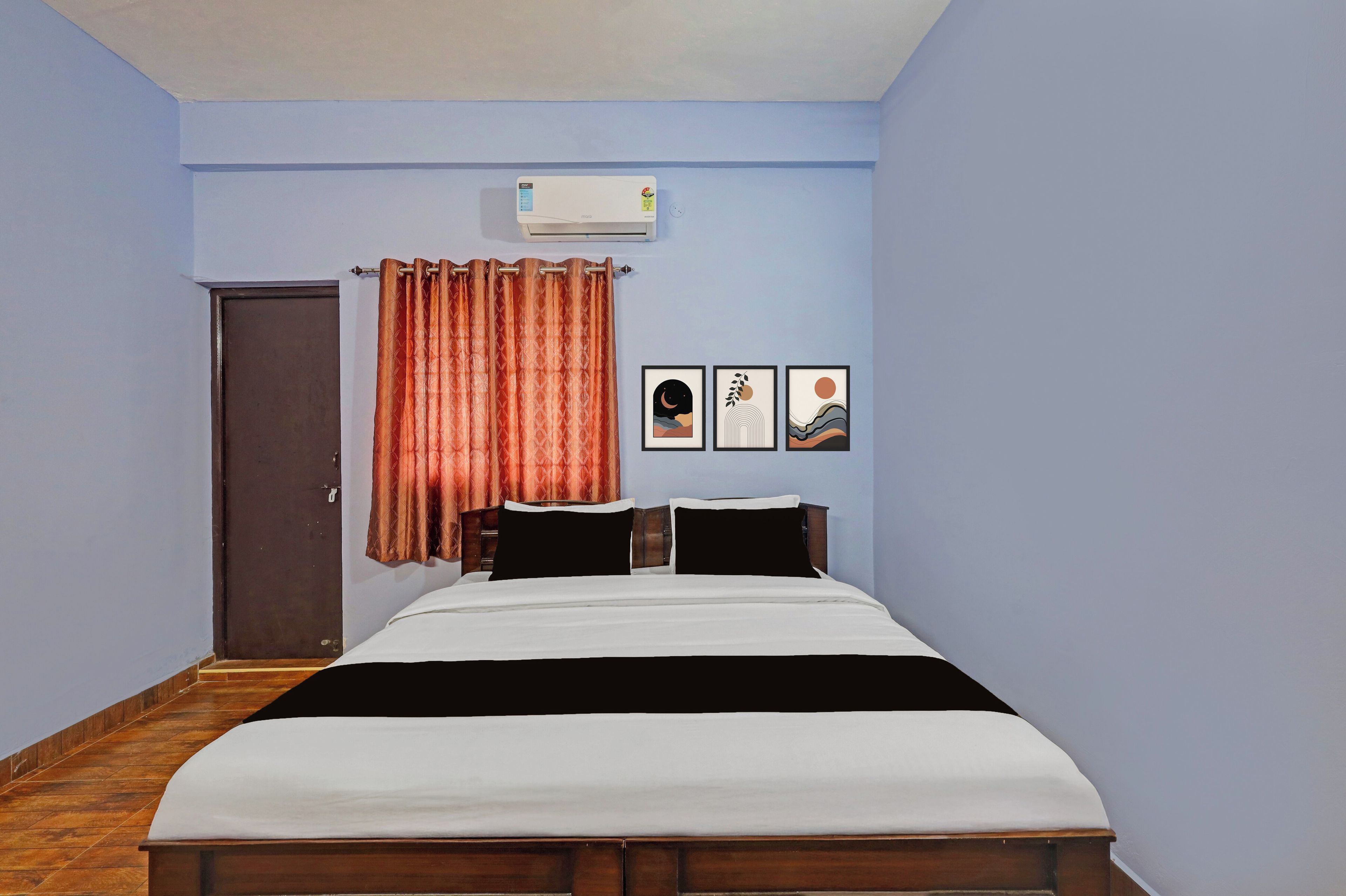 Une chambre à coucher avec un lit, une fenêtre avec des rideaux, une porte et des œuvres d’art murales.
