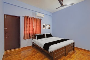 A bedroom with a wooden bed, a ceiling fan, a door, and a wall-mounted air conditioner.
