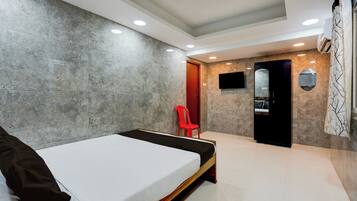 Un dormitorio moderno con una cama, una silla roja, un televisor y un espejo.