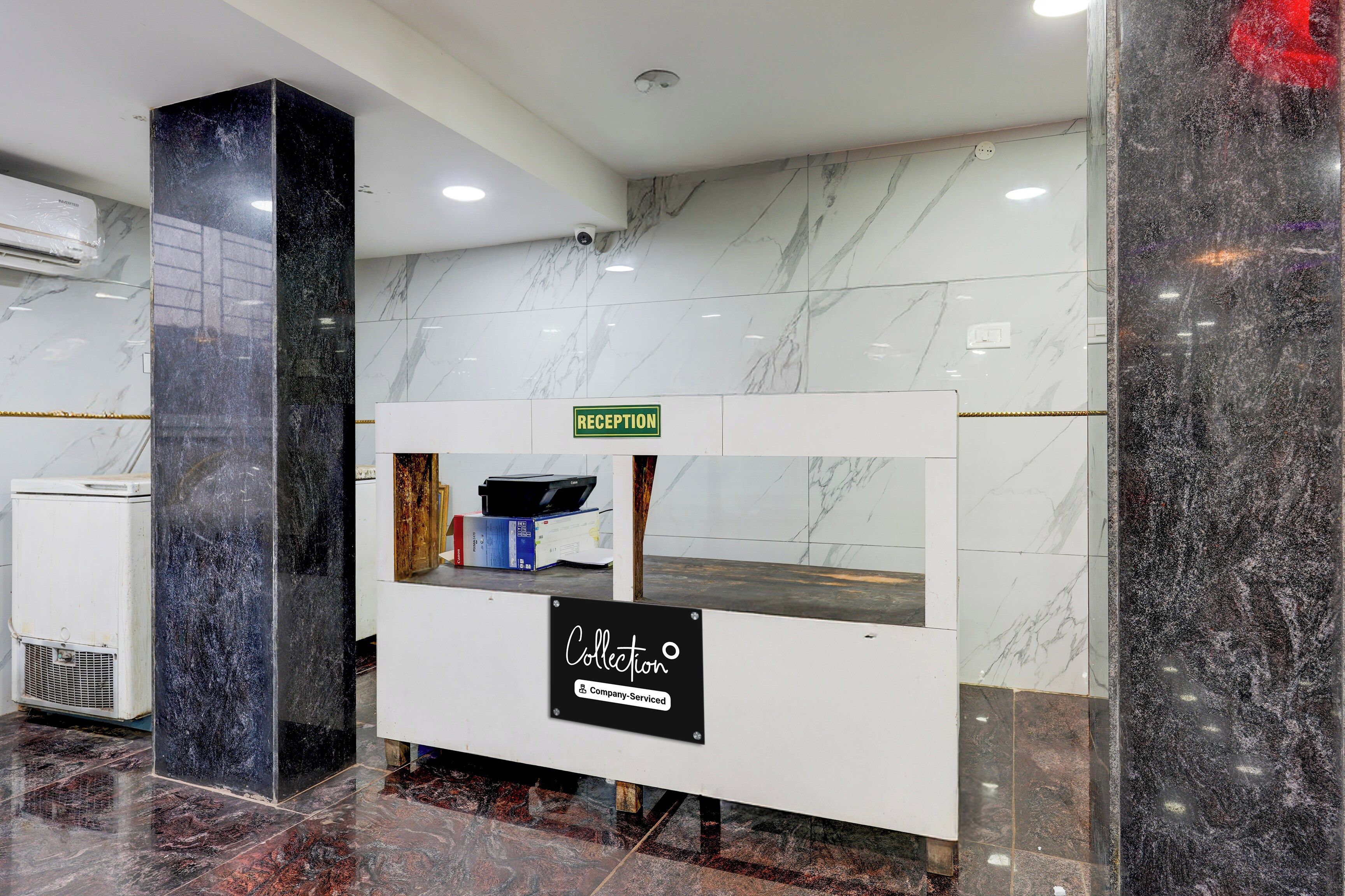 Un mostrador de recepción con un cartel que dice 'RECEPTION', un cartel que dice 'Collection' y una etiqueta 'Company-Serviced'.