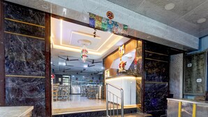 A hotel entrance with marble walls, a reception desk, and a staircase leading inside. - Collection O Karumariamman Temple (Chennai)