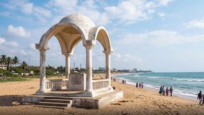 A beach with a historical monument featuring arches and a plaque. - Collection O Karumariamman Temple (Chennai)