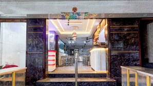 A hotel lobby with marble flooring, a reception desk, and a staircase leading to the upper floor. - Collection O Karumariamman Temple (Chennai)