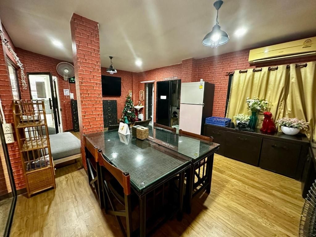 A dining area with a brick wall, a Christmas tree, a refrigerator, and a window with curtains.