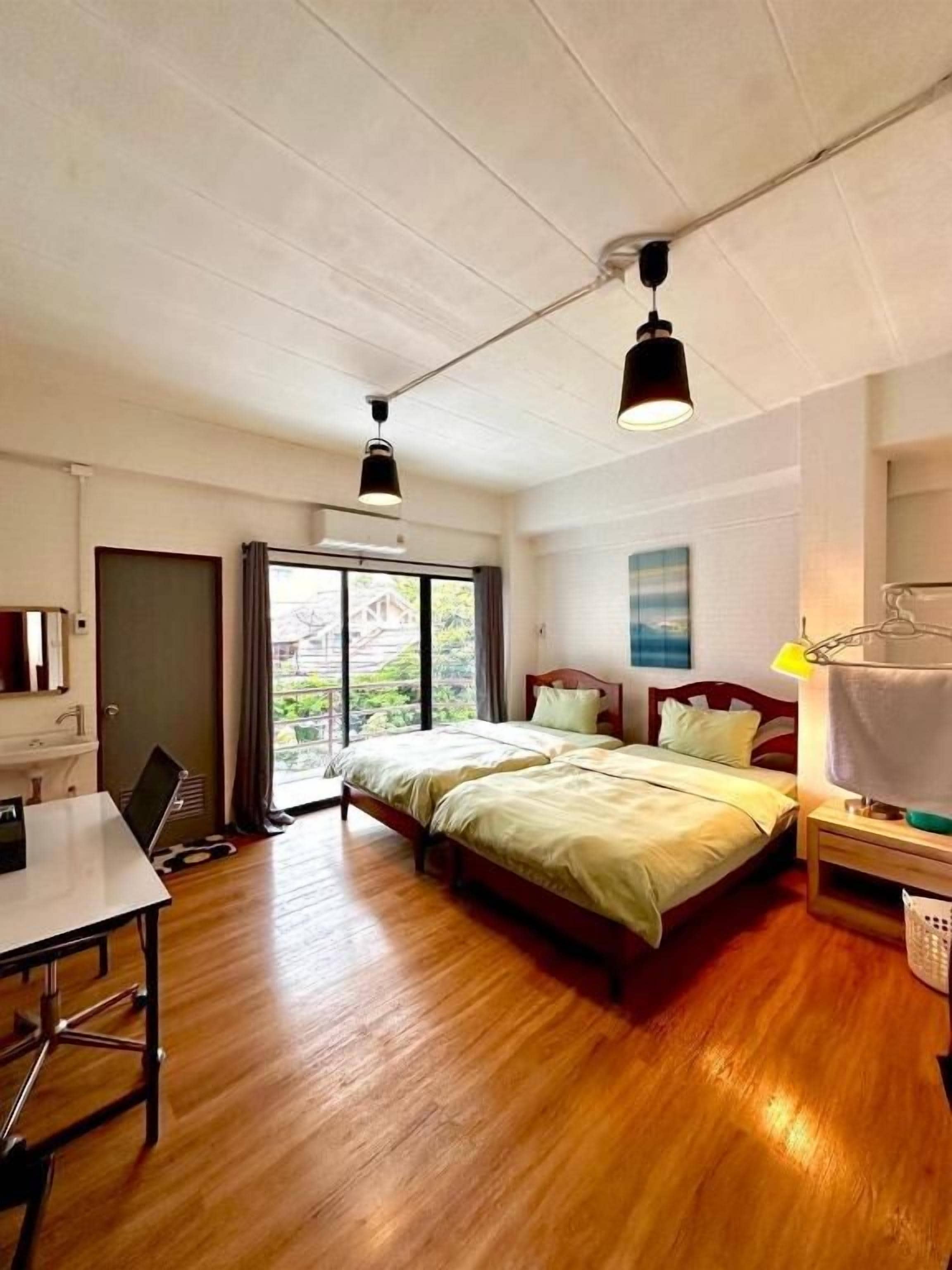 A hotel room with a bed, a desk, and a view through a window.