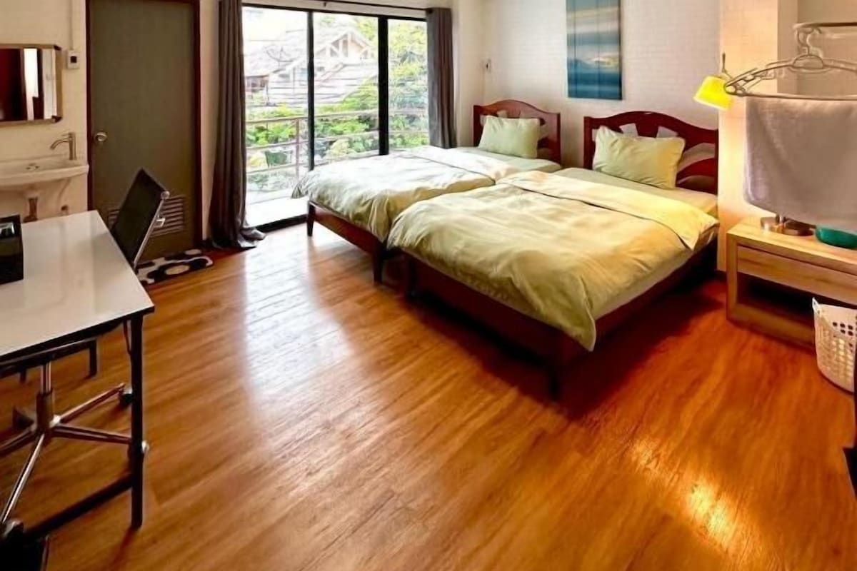 A hotel room with a bed, a desk, and a view through a window.