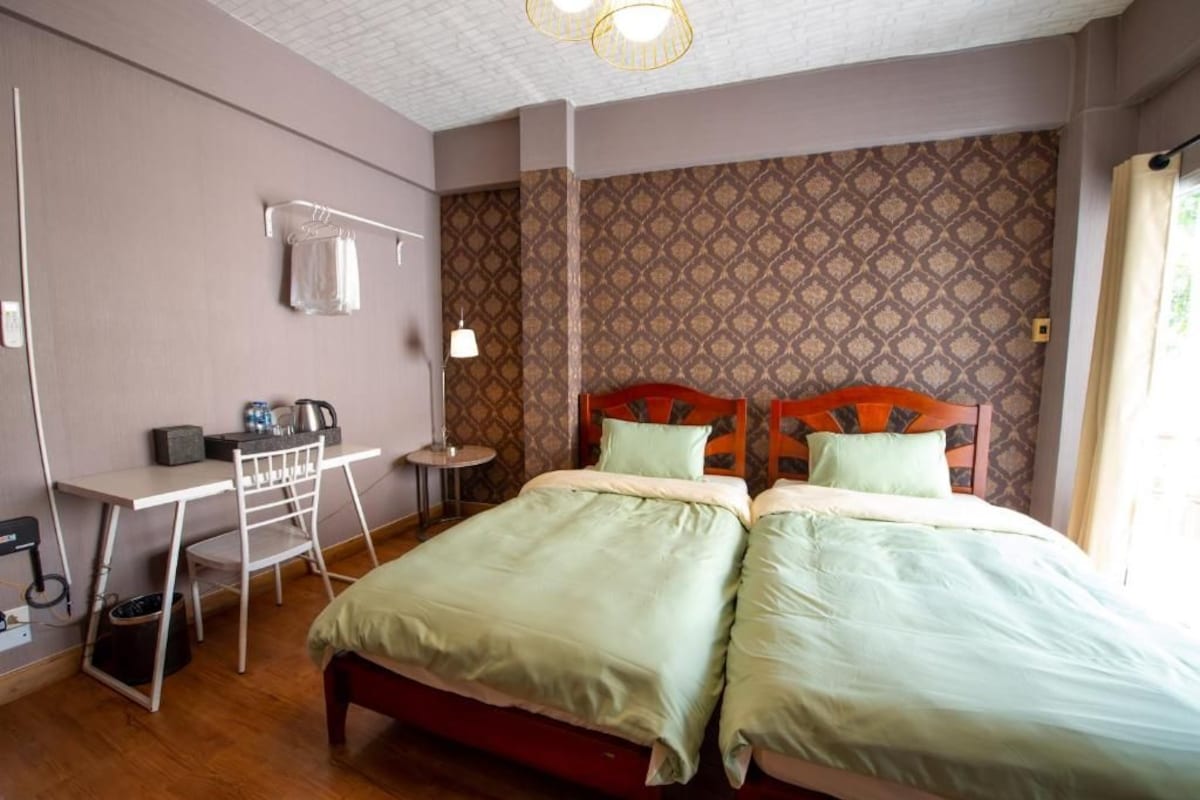 A hotel room with a bed, a desk, a chair, and a small table.