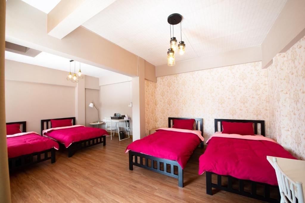 A hotel room with four beds, a desk, and a chair.