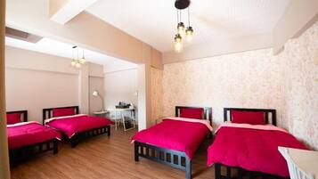 A hotel room with four beds, a desk, and a chair.