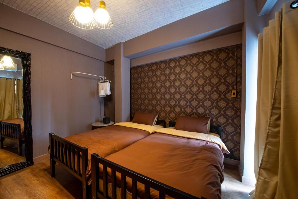 A hotel room with a bed, a bedside table, a lamp, and a patterned wall.