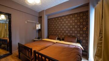 A hotel room with a bed, a bedside table, a lamp, and a patterned wall.