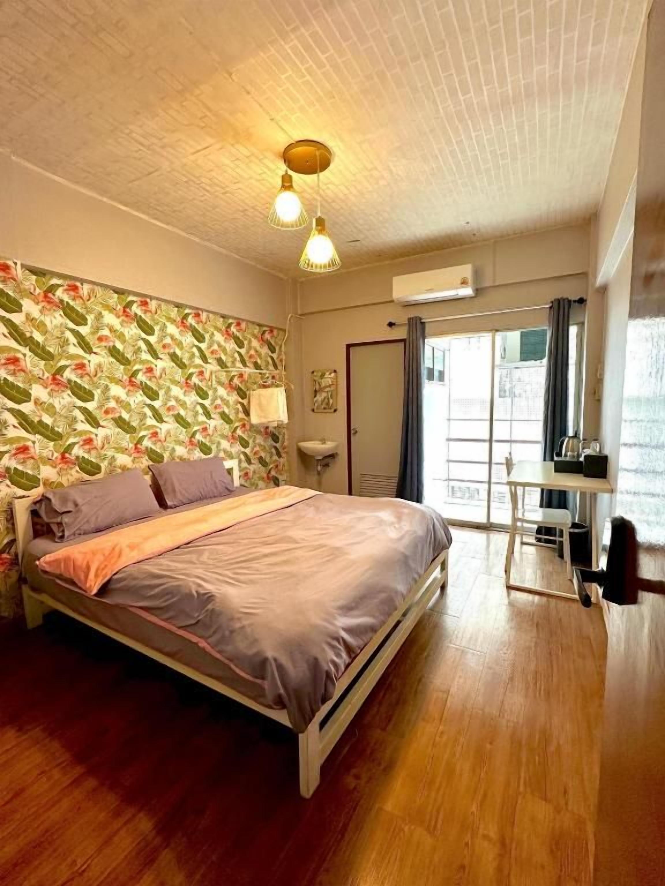 Ein Schlafzimmer mit Bett, Holzboden, Fenster und Tür.