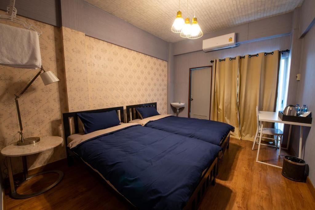 A bedroom with a double bed, bedside tables, a desk, a chair, a lamp, and a wardrobe.