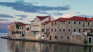 Um edifício à beira-mar com vários andares, fachada de pedra e telhados vermelhos.