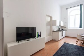 Eine moderne Küche mit Flachbildfernseher, weißen Schränken und einem Fenster mit Vorhang.