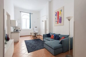 A modern living space with a kitchen, dining area, and a large gray sofa with colorful cushions. - Vittorio Elegant Two Bedroom Apartment (Roma)