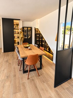 Ein moderner Essbereich mit einem Holztisch und Stühlen, einem Weinschränkchen und einer dekorativen goldenen Figur.