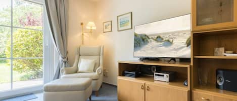 Quarto com uma janela ampla, sofá, televisão e um armário de madeira.
