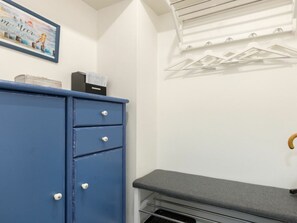 Ein Zimmer mit einer blauen Kommode, einer grauen Bank und einer weißen Wand mit einem gerahmten Bild.