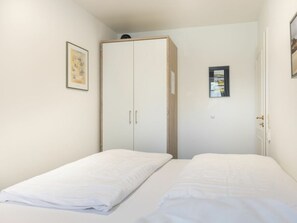 Ein Schlafzimmer mit zwei Betten, einem Kleiderschrank und einer Tür.