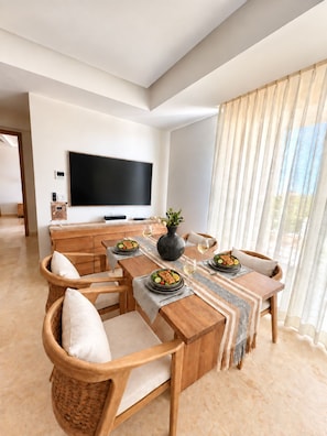 A modern dining area with a wooden table set for two, surrounded by wicker chairs. - Brand-New Luxury 2 BR with Stunning Marina Views in Marina Towers! (Puerto Vallarta)