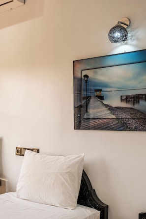 Ein Schlafzimmer mit einem Bett, einem Wandbild und einer Leuchte.