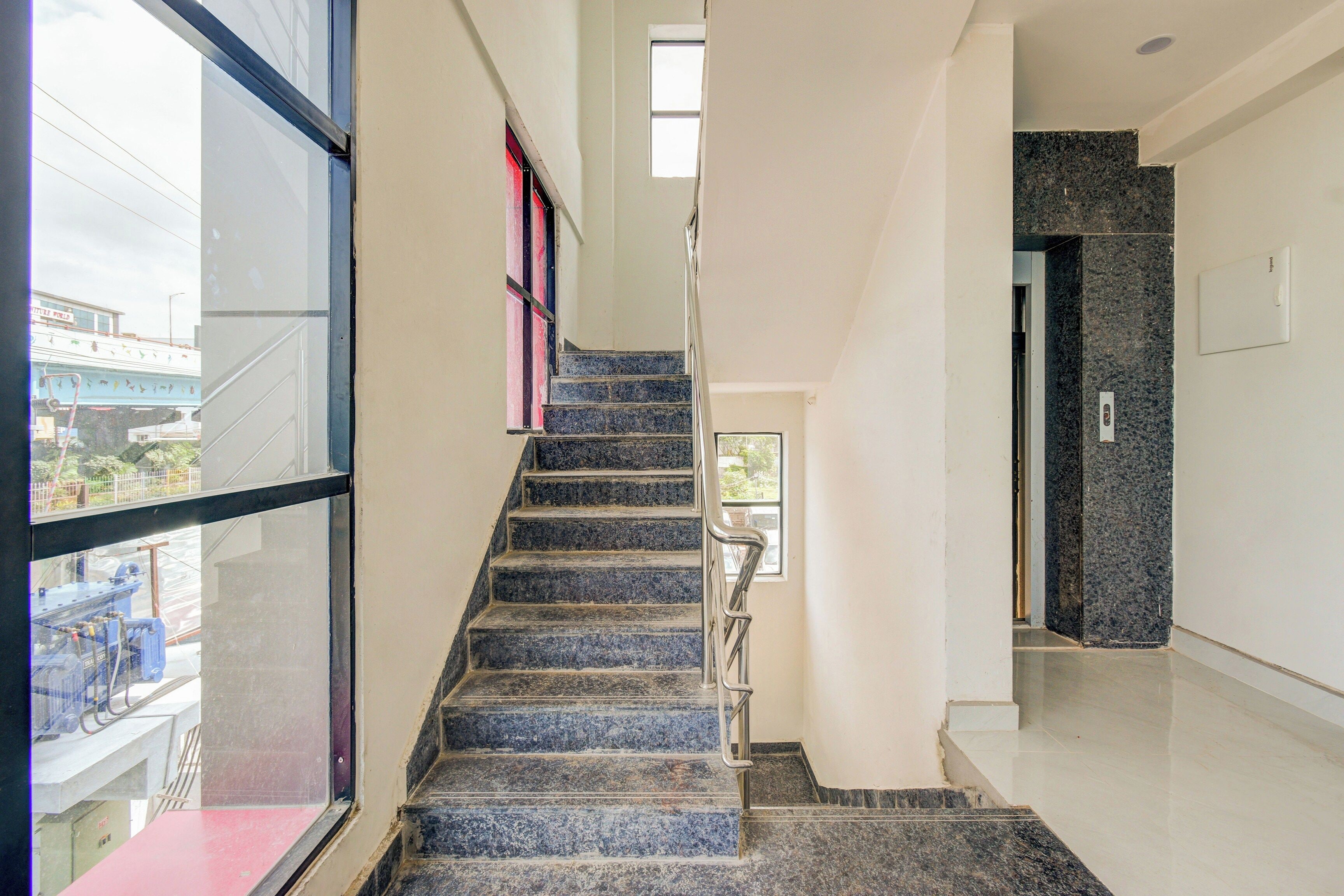 A staircase with a handrail, leading to a landing with a door and a light switch.