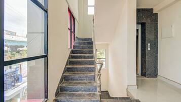 A staircase with a handrail, leading to a landing with a door and a light switch.