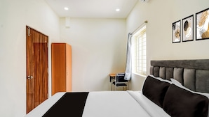 Een slaapkamer met een bed, een kledingkast, een bureau en een raam.