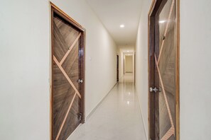 A corridor with wooden doors featuring geometric patterns and a tiled floor. - Townhouse Oak Hyderabad Victoria (Hyderabad)