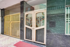 A building entrance with a metal gate and a glass door with decorative patterns. - Super Hotel O Mall Road Gwalior (Gwalior)