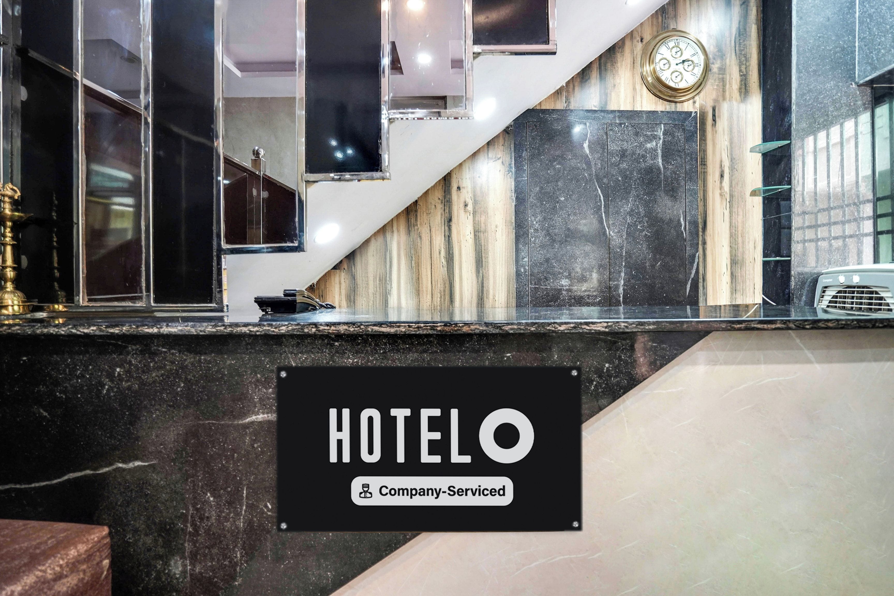Un'area della reception di un hotel con un bancone in marmo, una sveglia e un cartello che indica servizio aziendale.