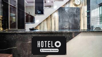 Un'area della reception di un hotel con un bancone in marmo, una sveglia e un cartello che indica servizio aziendale.