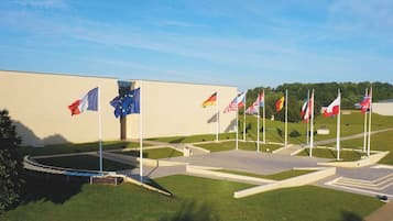 Un espace où sont exposés plusieurs drapeaux, dont le drapeau de l’Union européenne, et un bâtiment en arrière-plan.