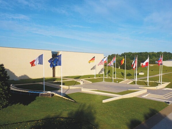 A flag display area with multiple flags, including the European Union flag, and a building in the background.
