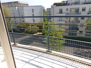 A balcony with a metal railing overlooking a residential area with buildings and trees.