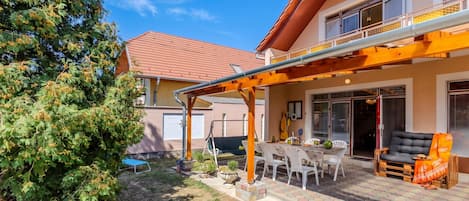 Una propiedad residencial con porche cubierto, mobiliario de exterior y jardín.