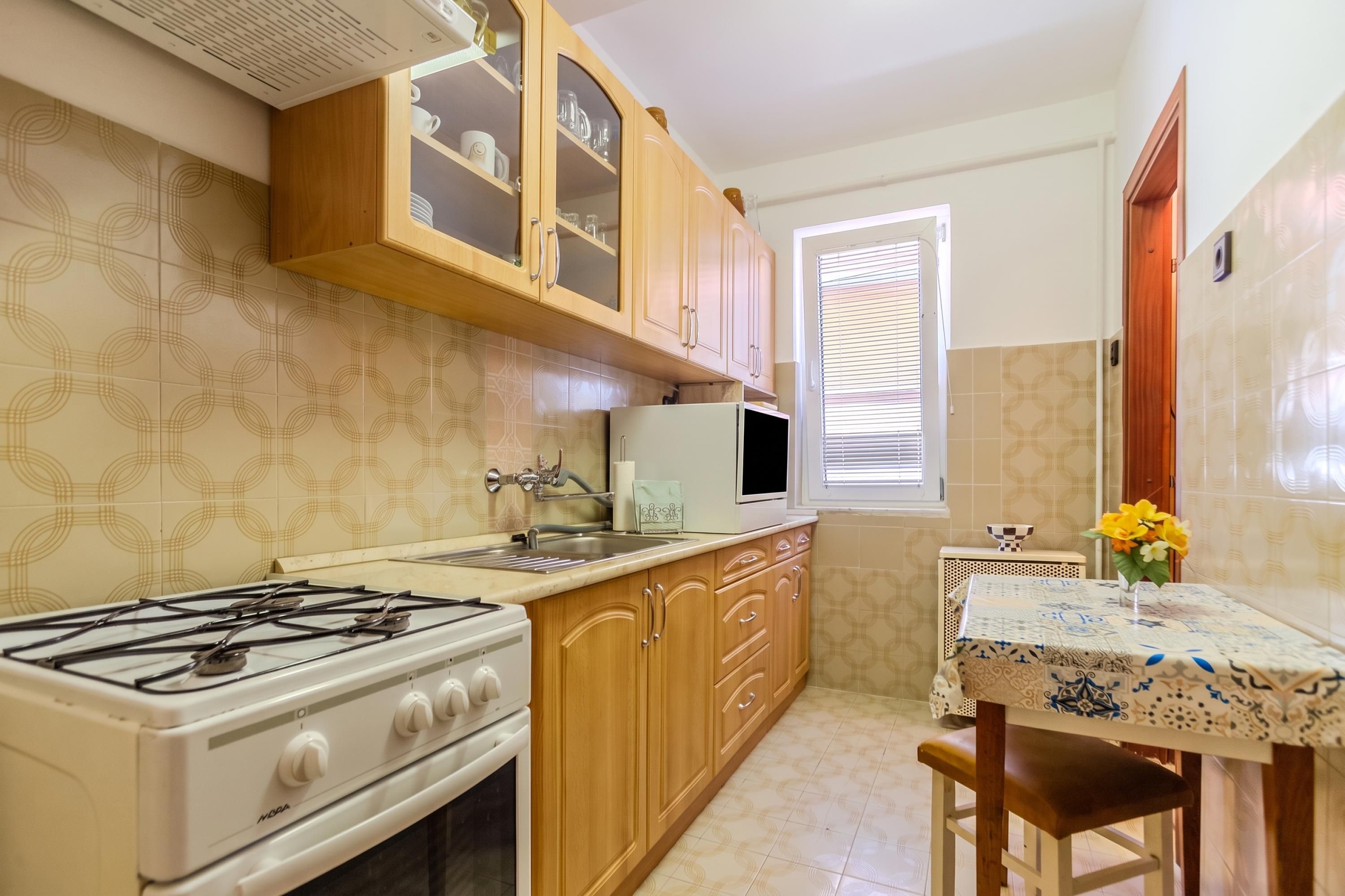 Una cocina con estufa, armarios, un lavabo y una ventana con persianas.