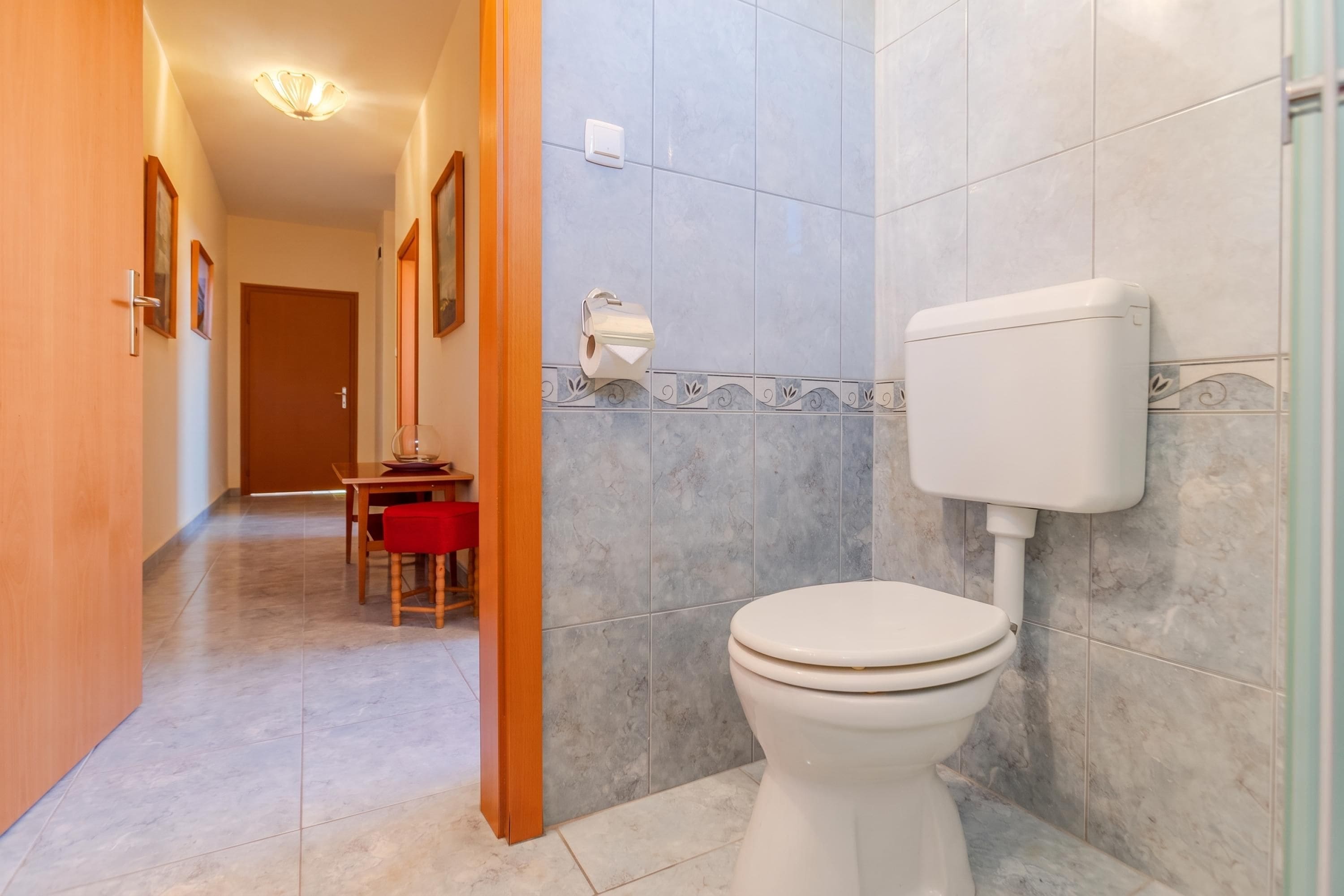 Un baño con inodoro, zona de ducha y suelo de baldosas.
