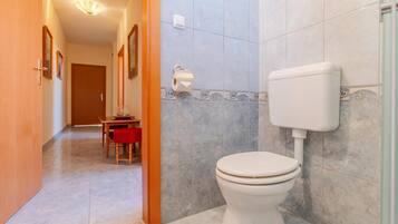 Un baño con inodoro, zona de ducha y suelo de baldosas.