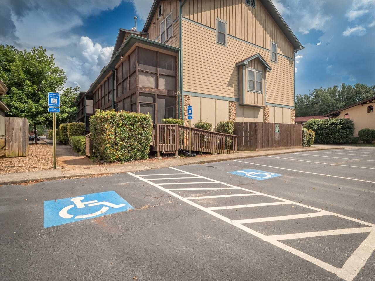 Een parkeerplaats met parkeerplaatsen voor gehandicapten en een gebouw met een houten gevel.