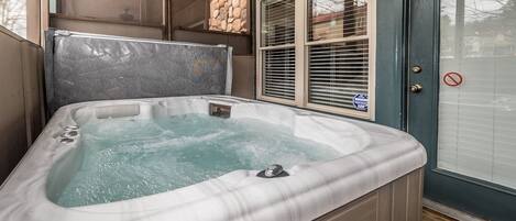 A hot tub with a stone wall and a door with a no entry sign.