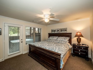 A bedroom with a bed, a nightstand, a ceiling fan, and a door with blinds. - 🌷 Das Tulip of Helen. Center of town, Ground floo (Helen)