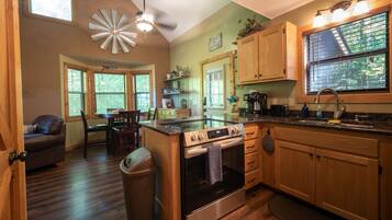 A kitchen with wooden cabinets, a stove, and a dining area with a table and chairs.