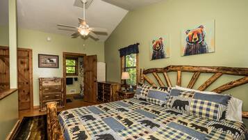 A bedroom with a bed, a ceiling fan, a wooden headboard, and a window with a view of greenery.