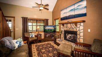 A cozy living room with a stone fireplace, a flat-screen TV, and comfortable seating.