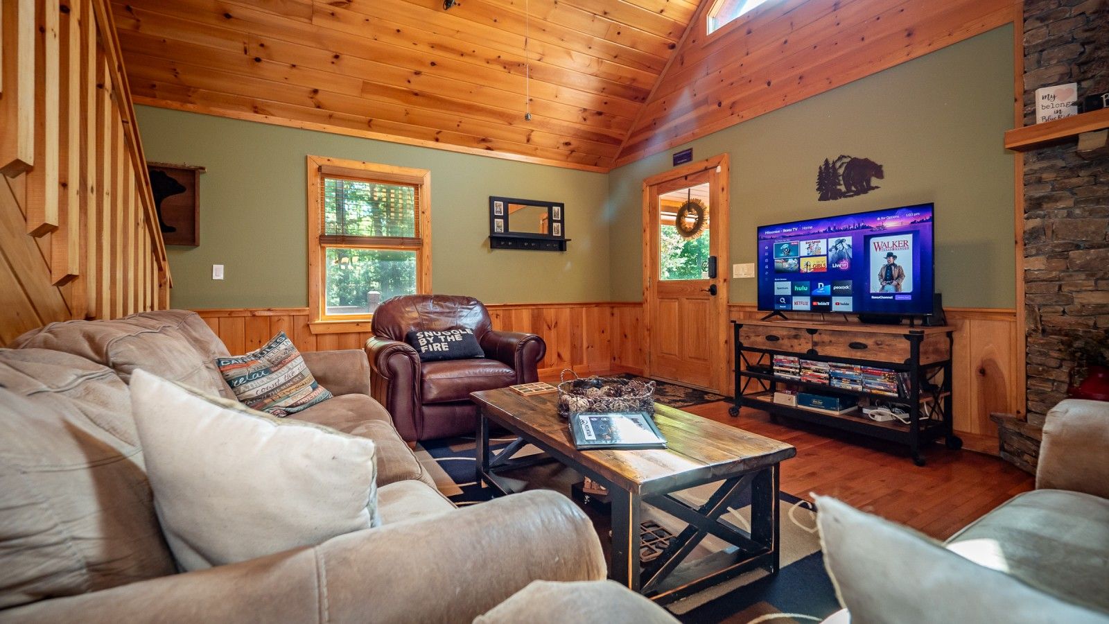 A cozy living room with a leather armchair, a wooden coffee table, and a television on a stand.